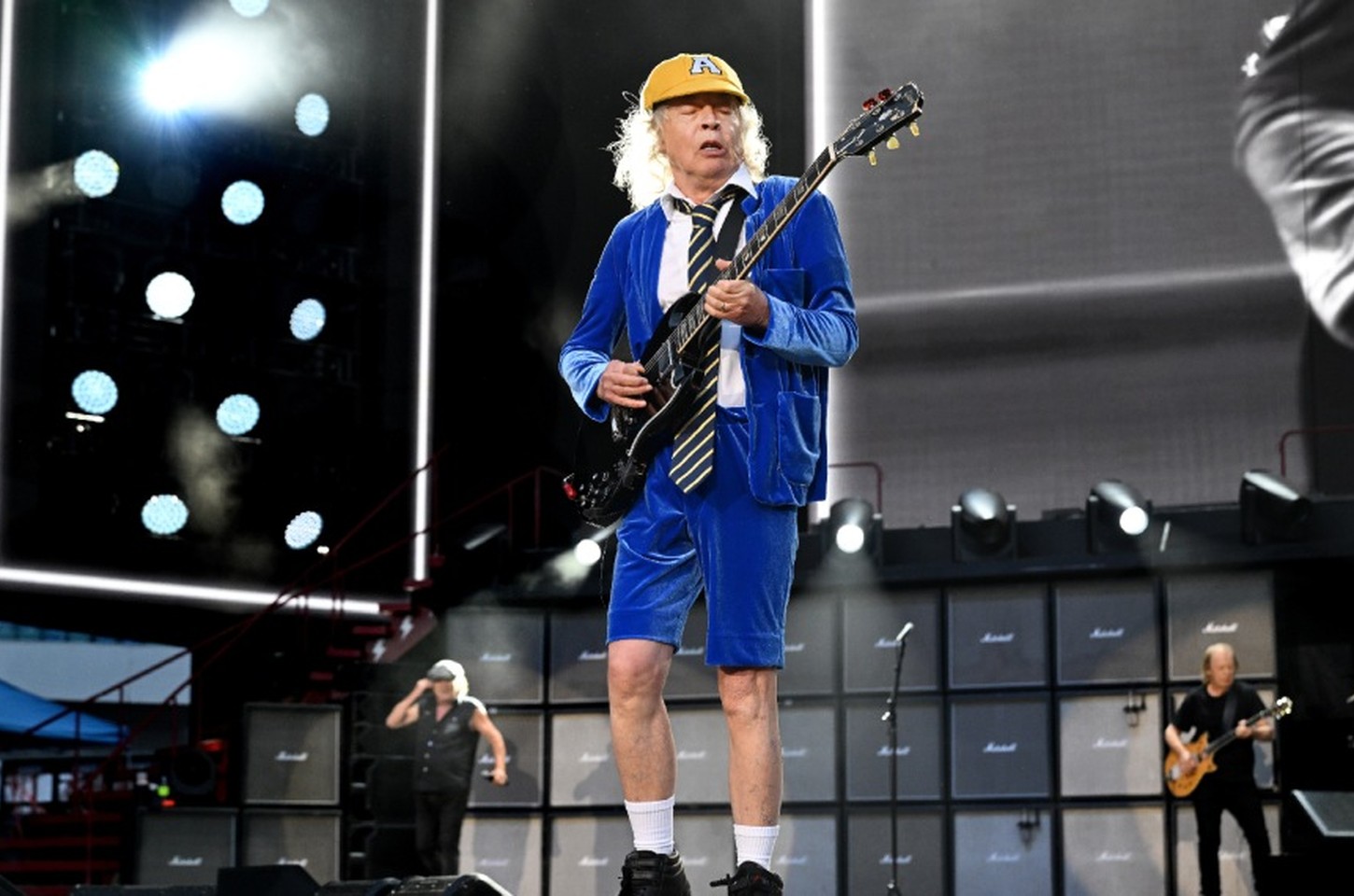 Por que Angus Young usa uniforme escolar no palco? História por trás do visual